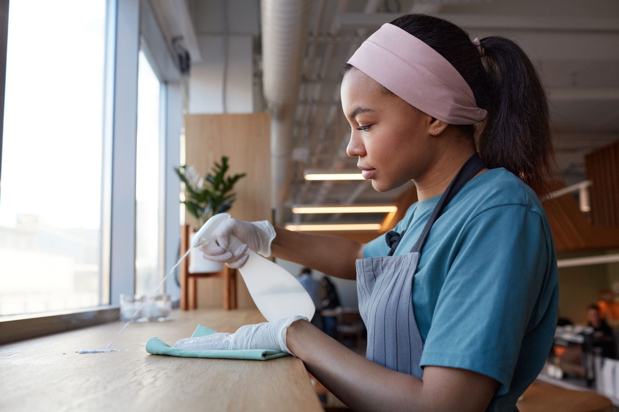 Cleaning-Services-Fort-Lauderdale-ide-view-portrait-young-african-american-woman-cleaning-windows-with-sanitizer-cafe-copy-space-min-scaled